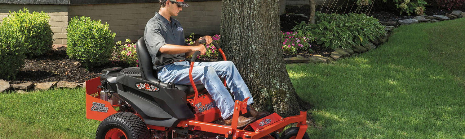 Man riding a orange 2022 Bad Boy Magnum mower around a lawn