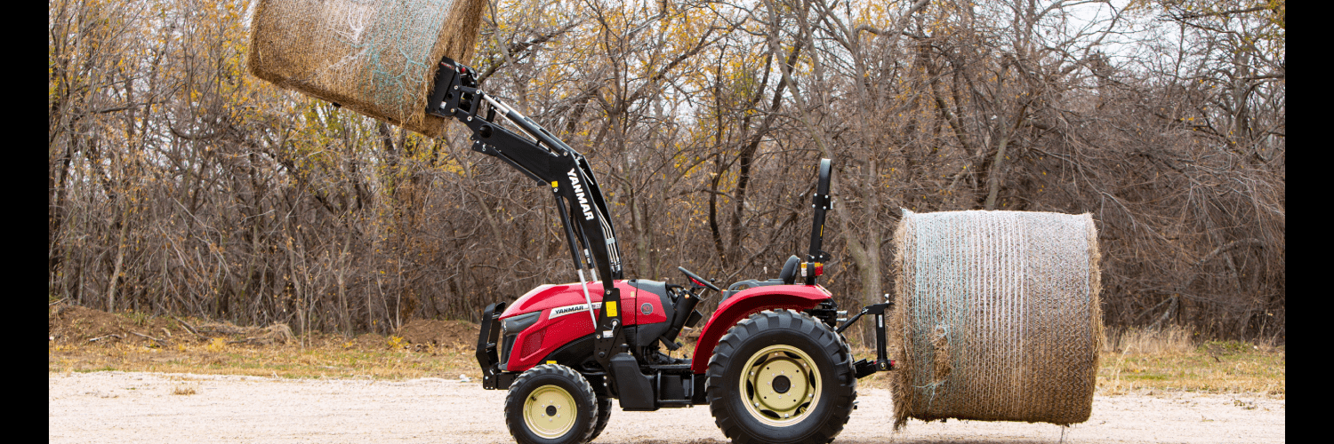 Red 2022 Yanmar tractor lifting a bale of hay